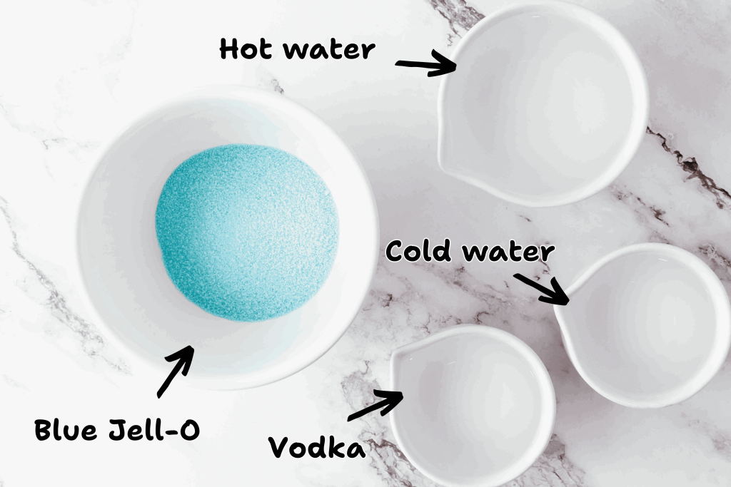 A top-down view of four white bowls on a marble surface, labeled for making Vodka Jello Shots: Blue Jell-O powder, hot water, cold water, and vodka—perfect for festive 4th of July celebrations. Arrows and handwritten labels identify each ingredient.