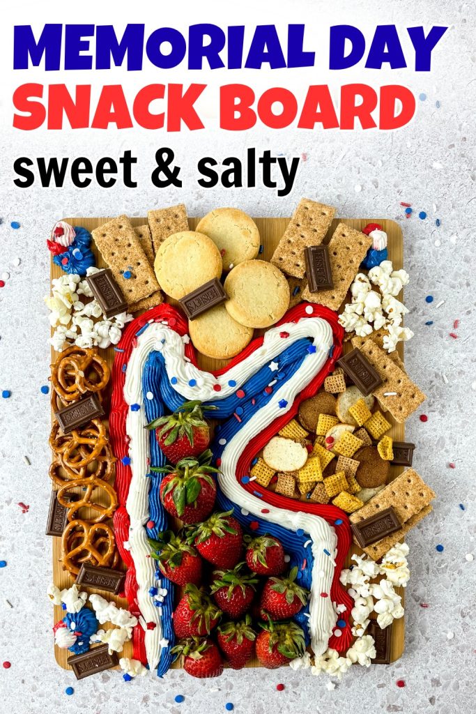 A festive Memorial Day Snack Board with red, white, and blue frosting, strawberries, pretzels, popcorn, cookies, Chex mix, graham crackers, and chocolate pieces arranged on a wooden board and topped with sprinkles.