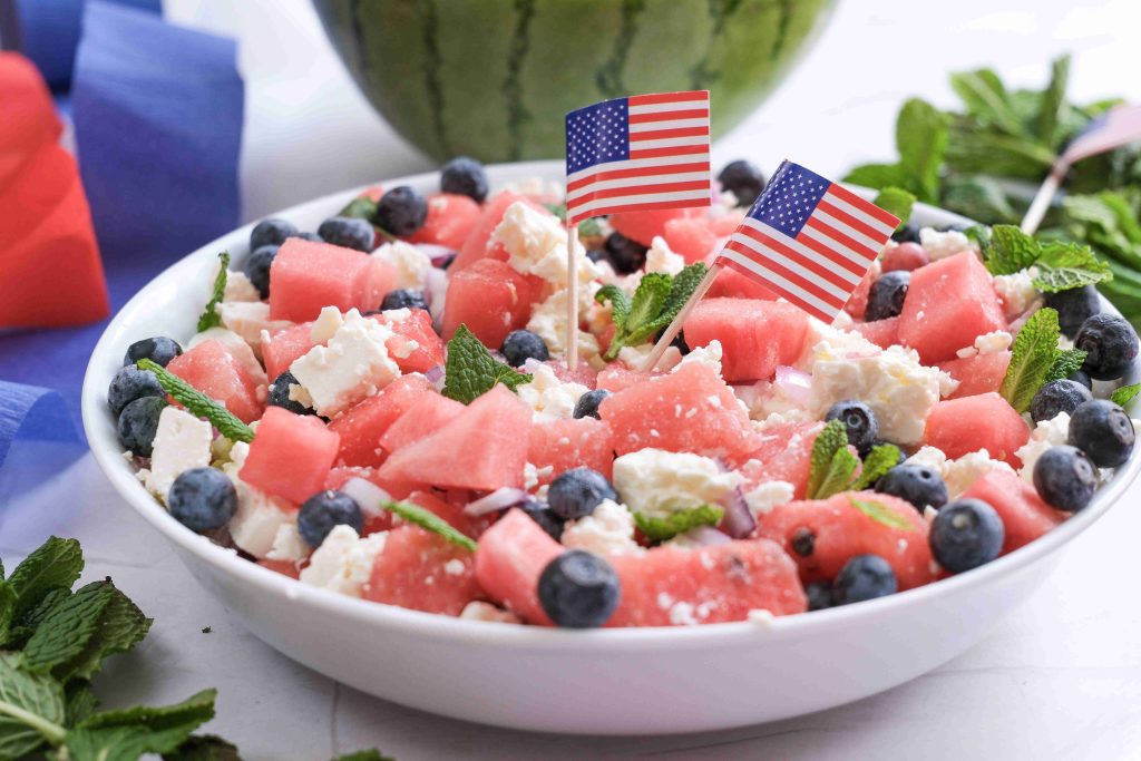 A festive Watermelon Blueberry Feta Salad, topped with fresh mint and tiny American flags, makes the perfect red white blue salad for your summer BBQ. Fresh mint leaves and a glimpse of juicy watermelon complete the scene.