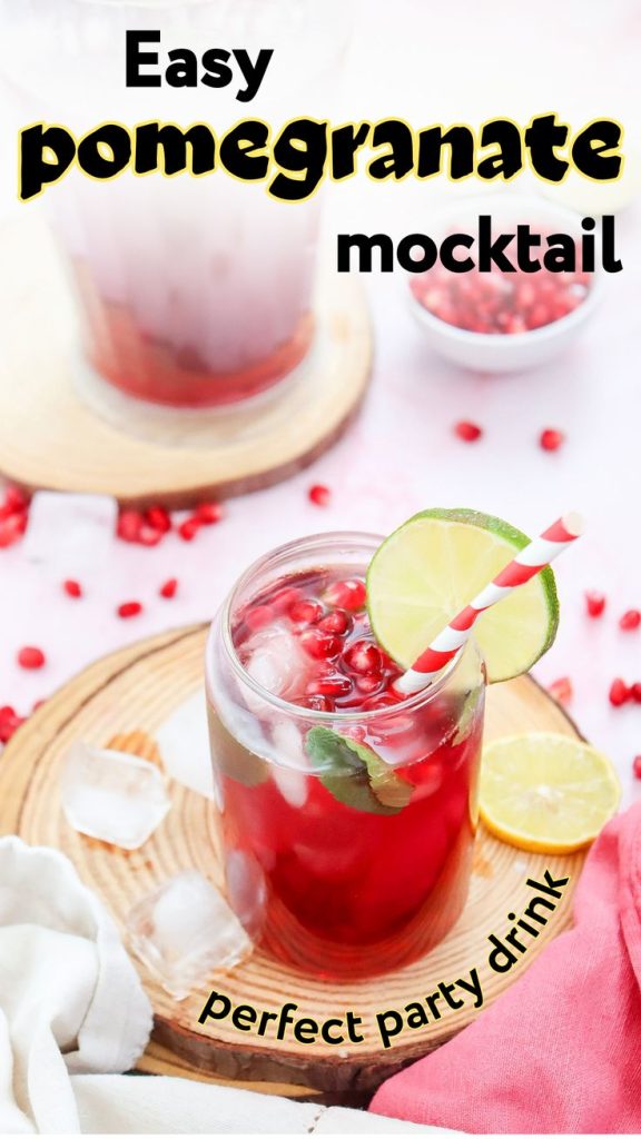 A vibrant glass of mocktail with pomegranate juice recipe, ice, pomegranate seeds, a lime slice, and a striped straw sits on a wooden coaster. More pomegranate seeds and another drink are in the background. Text reads: “Easy pomegranate mocktail.