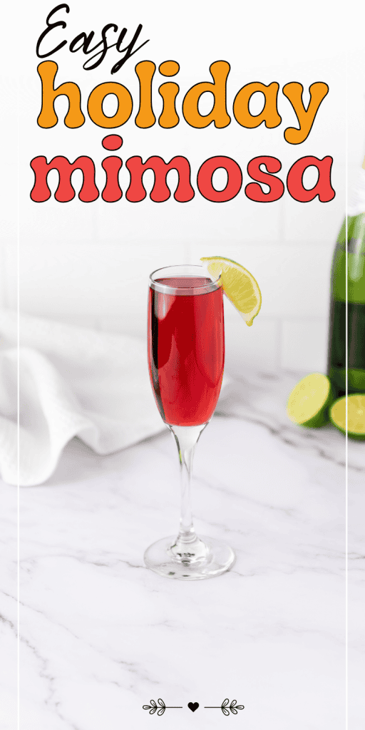 A champagne flute filled with a red holiday mimosa, garnished with a lime wedge, sits on a marble surface beside limes, a bottle, and towel—a festive setup perfect for Christmas morning mimosas. Text above reads “Easy holiday mimosa.”.