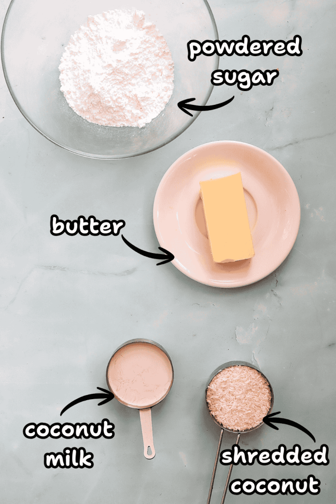 A bowl of powdered sugar, a plate with a stick of butter, coconut milk, and shredded coconut sit on a light blue surface—perfect ingredients for making a delicious coconut Christmas cake.