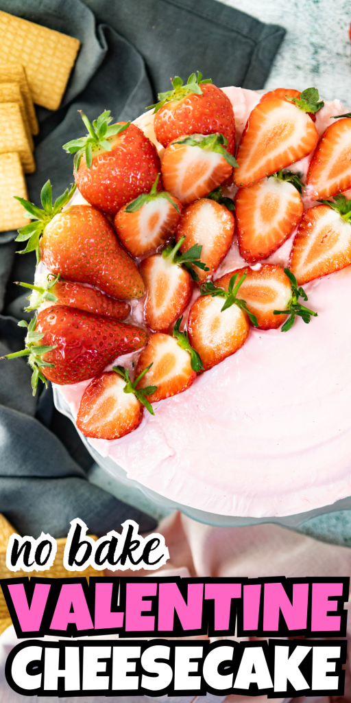 A pink no-bake cheesecake for Valentine’s Day topped with fresh strawberries, sitting next to wafer cookies and a dark green napkin. The text on the image reads no bake Valentine cheesecake.