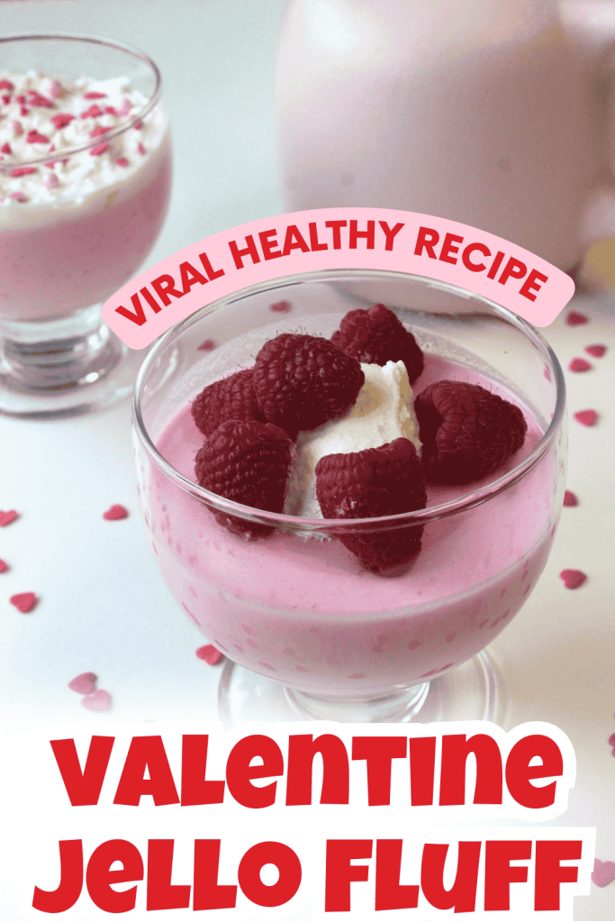 A glass dessert cup filled with pink Valentine's Day Jello Fluff, topped with whipped cream and raspberries. Heart-shaped sprinkles are scattered around. Text reads: Viral Healthy Recipe and Valentine Jello Fluff.