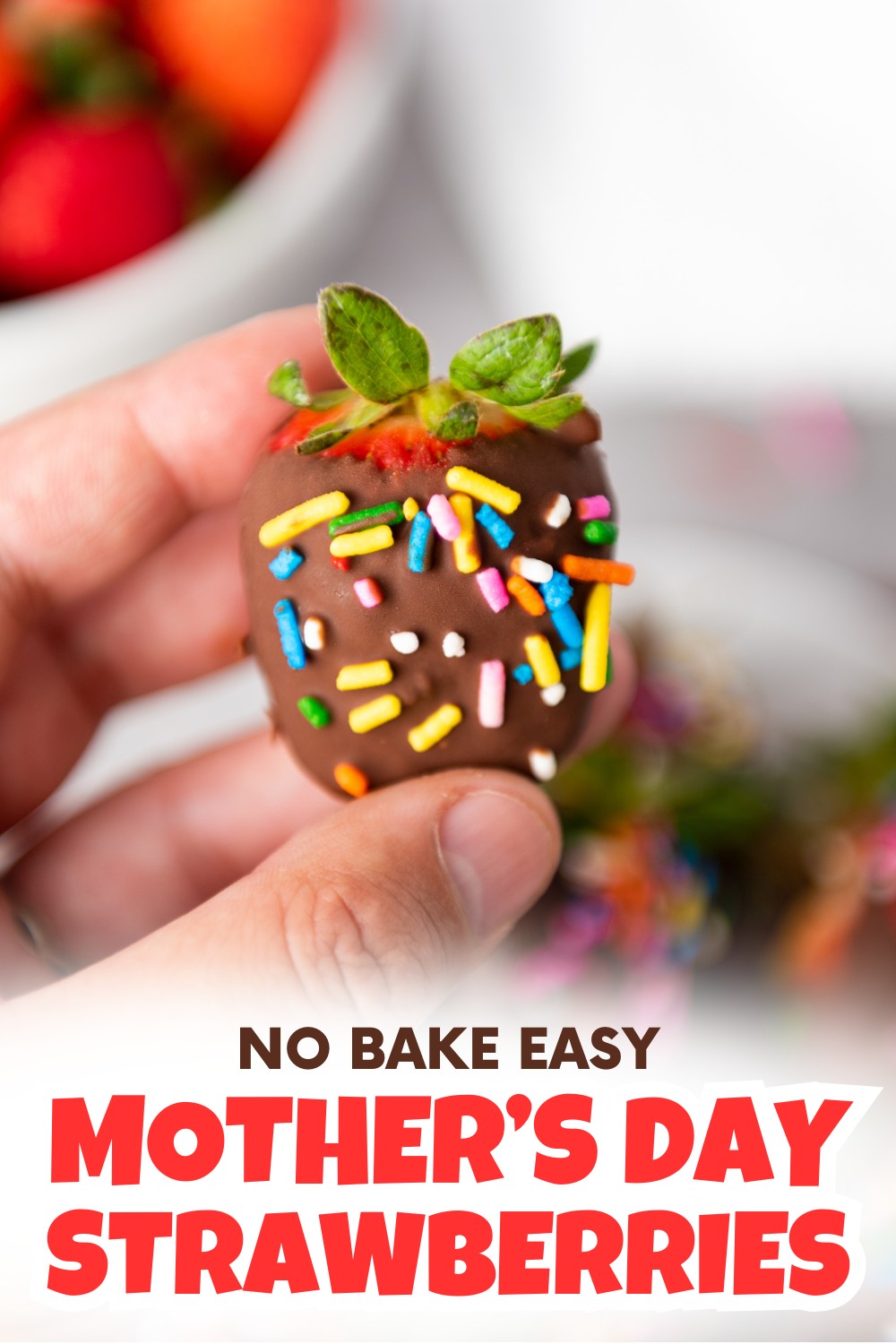 A hand holds a chocolate-covered strawberry topped with colorful sprinkles. The background shows more treats and the text Chocolate Covered Strawberries For Mothers Day in bold red letters at the bottom.