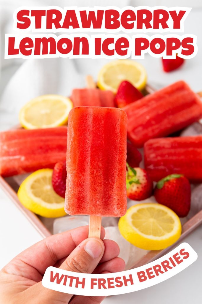 A hand holds a bright red ice pop in front of a tray filled with more pops, fresh strawberries, lemon slices, and ice cubes. Bold text reads: Strawberry Lemonade Ice Pops — an easy strawberry popsicles recipe with fresh berries.