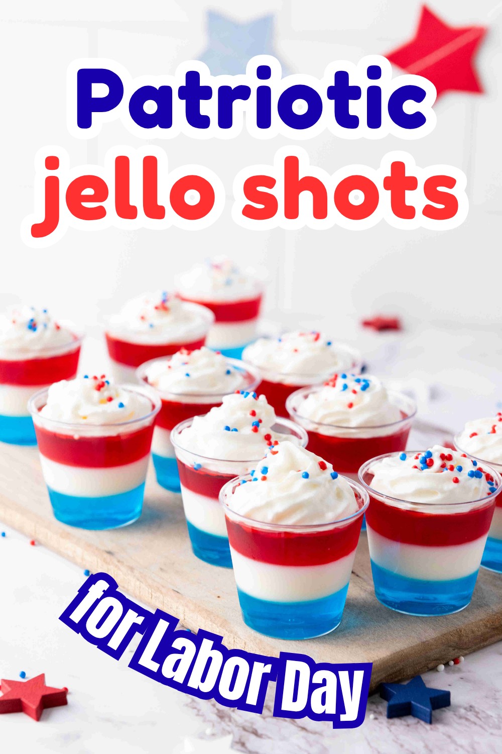 Nine red, white, and blue layered Labor Day Jello Shots with whipped cream and sprinkles sit on a tray. Text reads: “Patriotic jello shots for Labor Day.” Red and blue stars decorate the background.