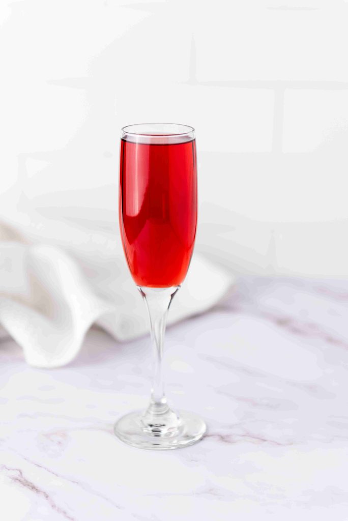 A single flute glass filled with a bright red thanksgiving cranberry cocktail.